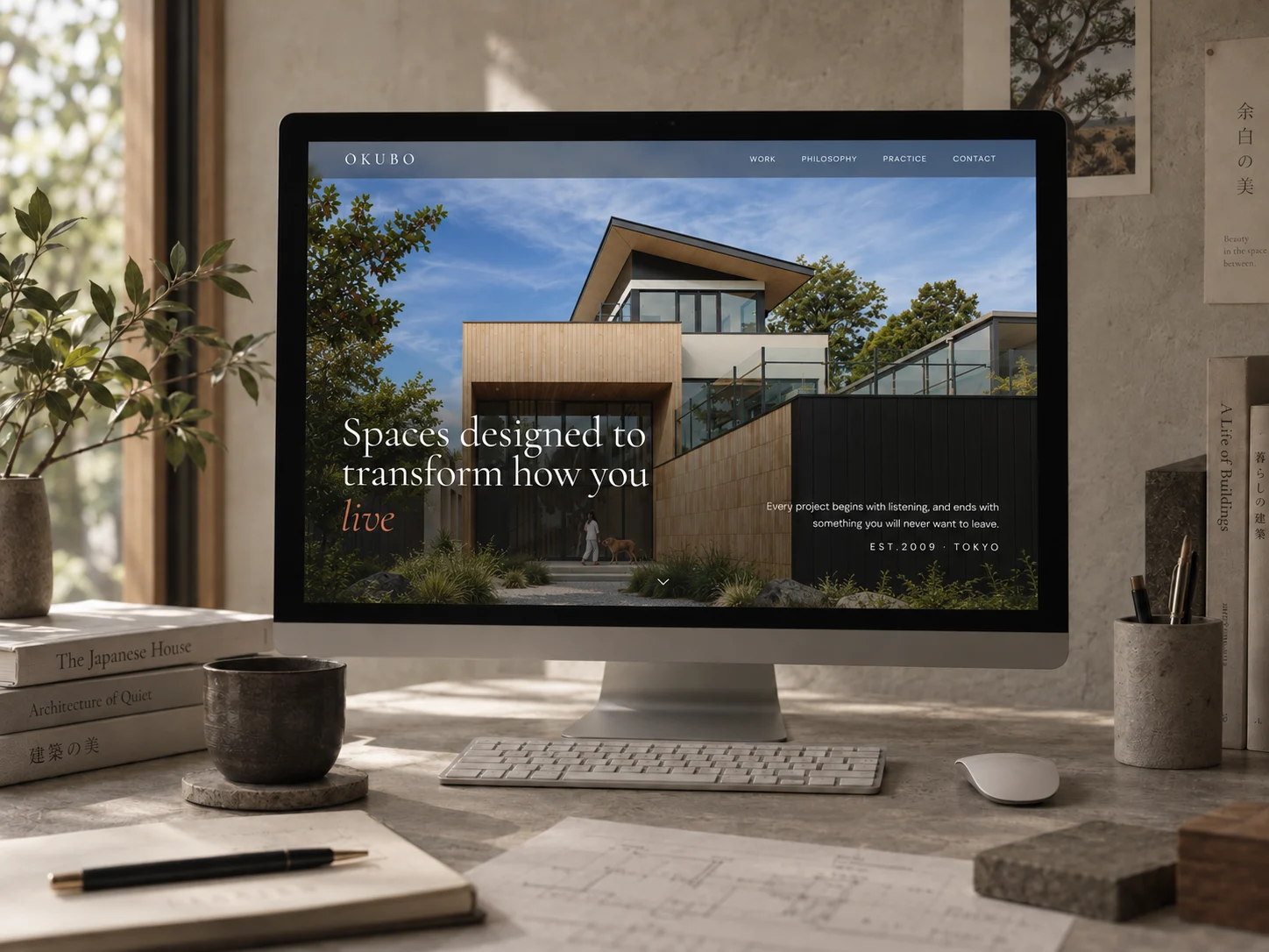 Ōkubo's homepage on a desktop monitor, with architecture books on the desk