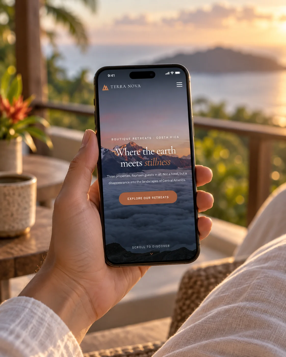 Terra Nova's homepage on a phone held on a balcony at sunset